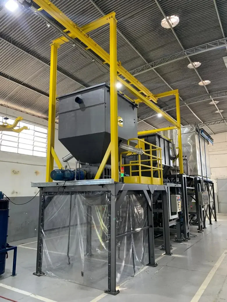Unidade de gaseificação instalada e montada em galpão industrial, com estrutura amarela de acesso e sistema de alimentação de resíduos